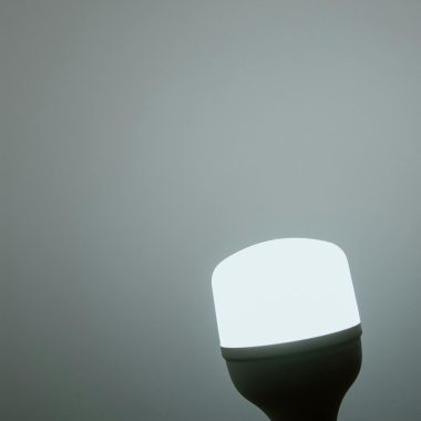 A glowing LED light bulb against a minimalist grey background, emphasizing simplicity and efficiency.