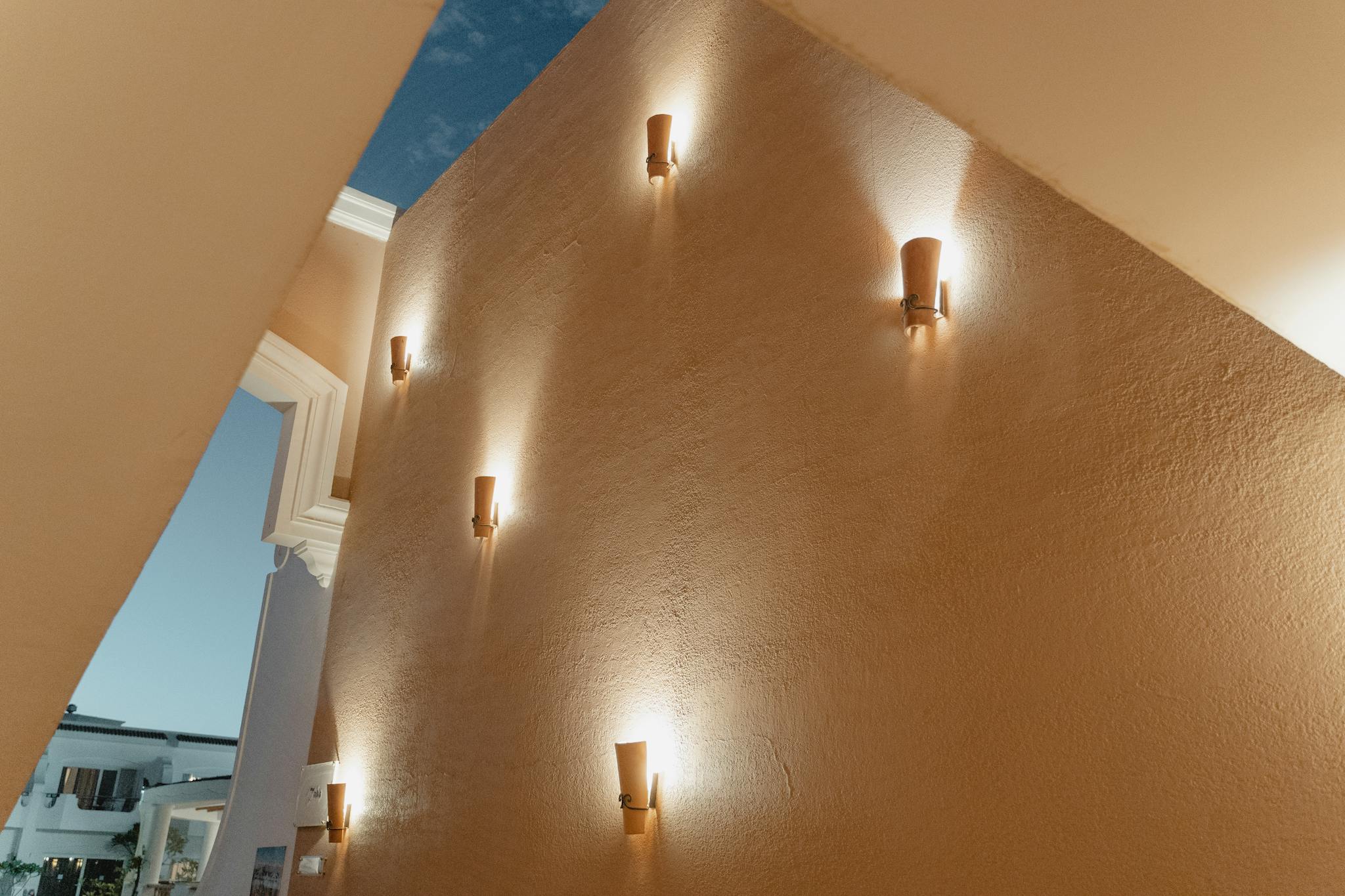 Elegant low angle shot of sconces lighting a beige interior wall, creating a warm and modern ambiance.